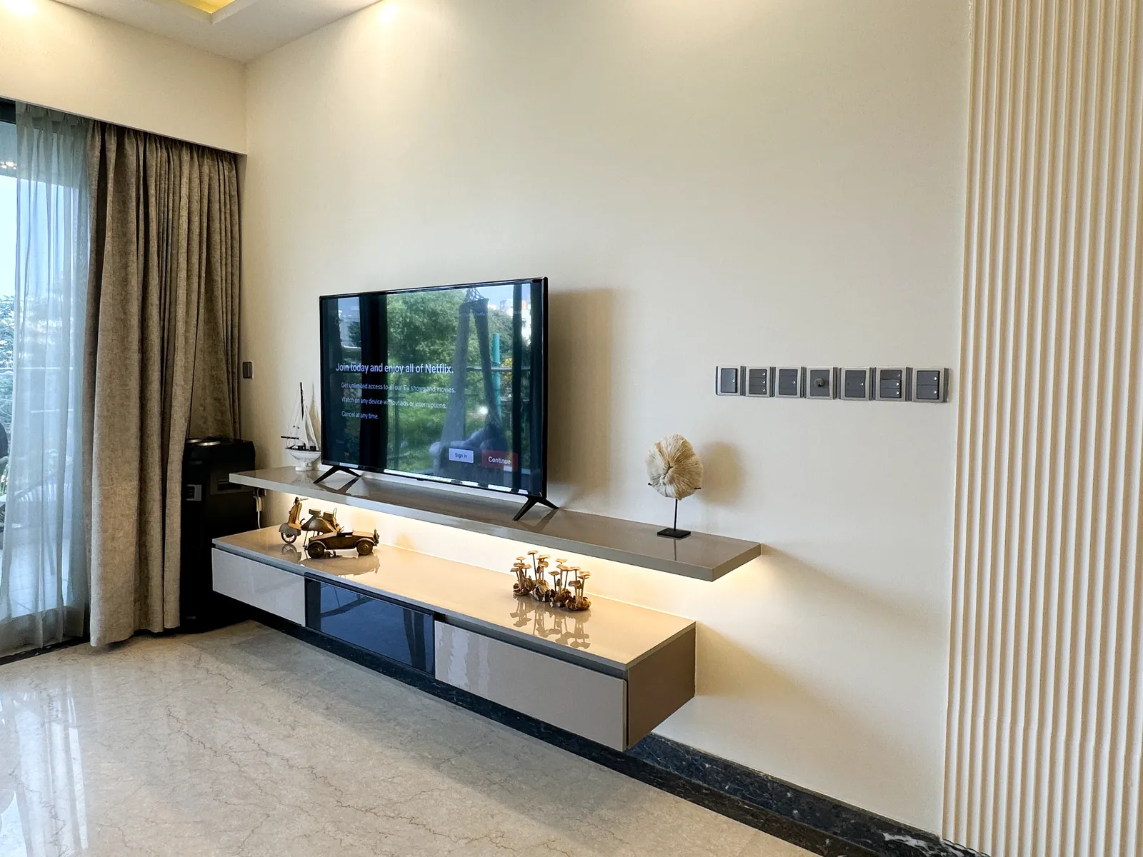 TV wall with floating lit console and fluted panel — Somani's Residence